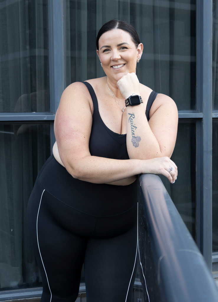 Coach is posing in a black workout outfit.